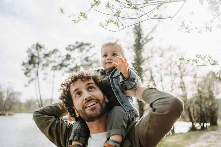 Un homme tenant un bébé dans ses bras dans un parc.
