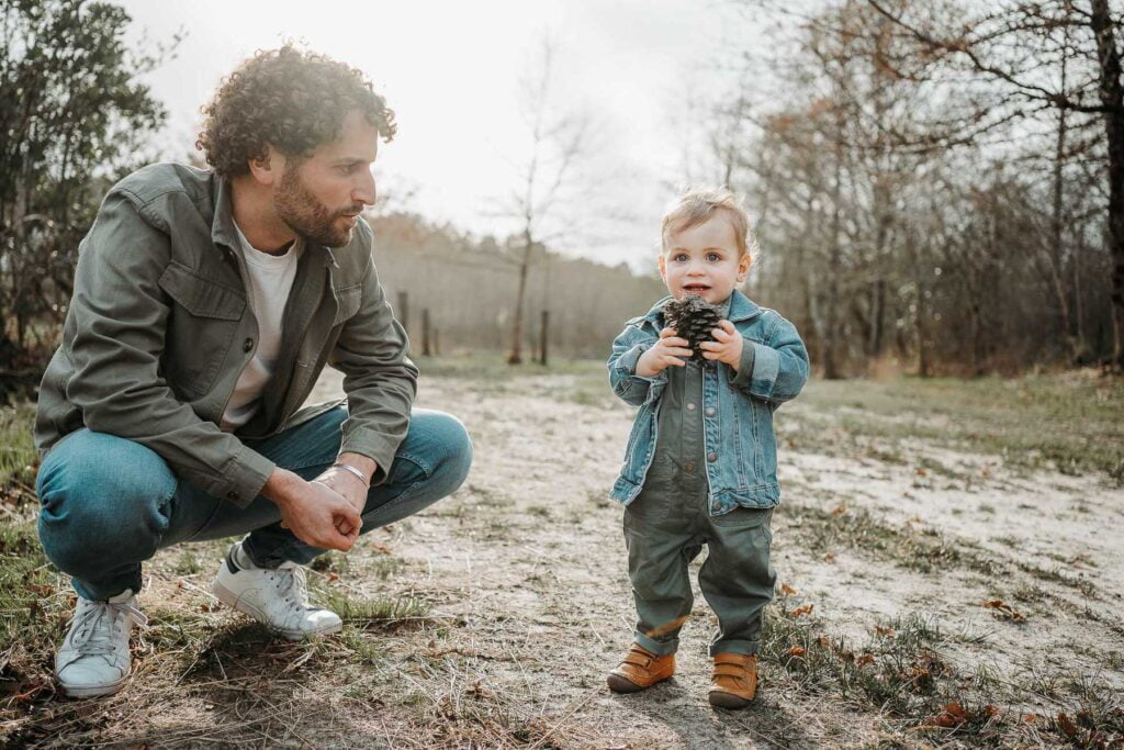 Un homme tient un appareil photo tandis que son fils se tient sur un chemin de terre.