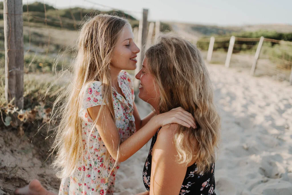 Une mère et sa fille s'embrassant sur la plage.