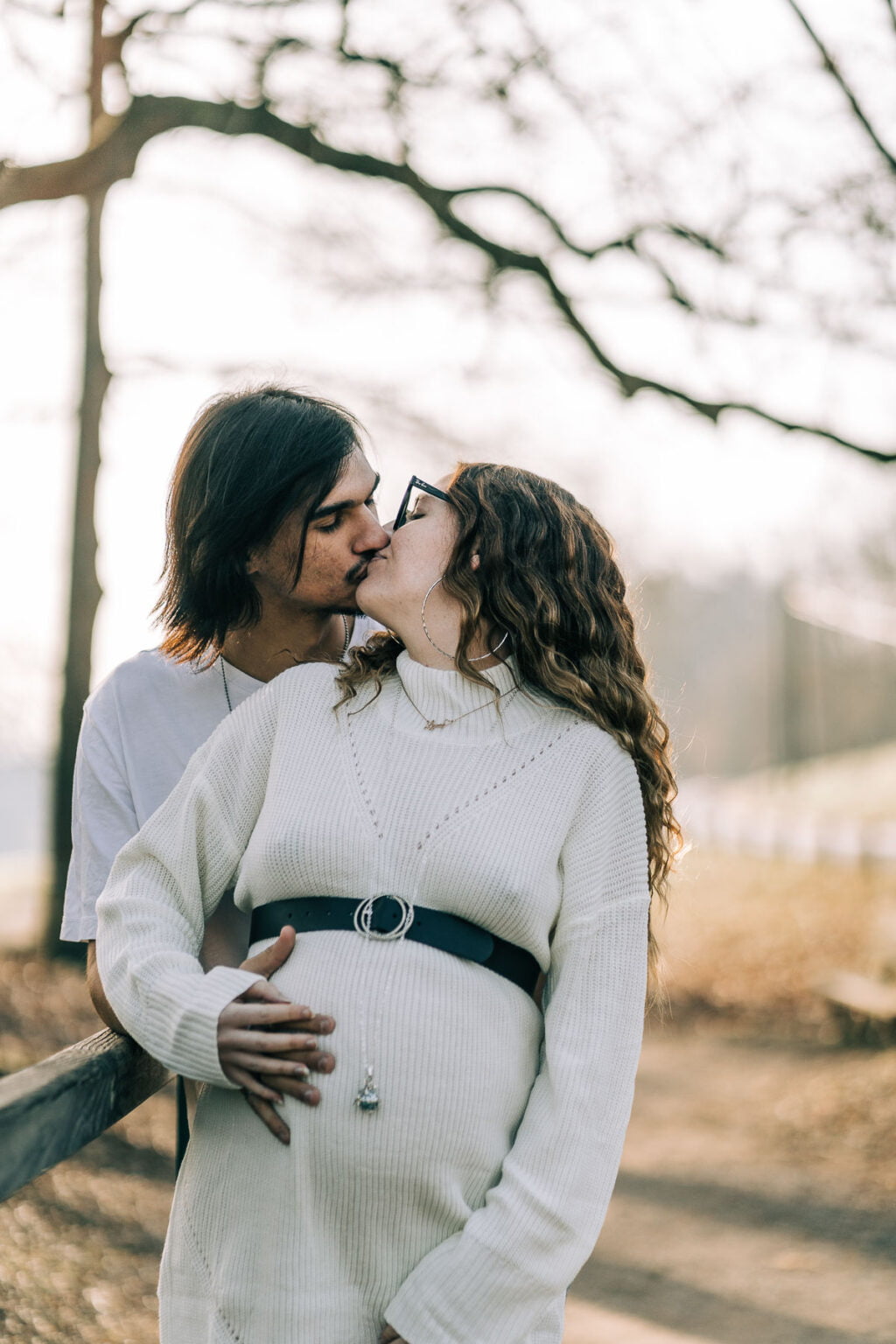 Femme enceinte dans un sous-bois doré, robe fluide et lumière chaude.