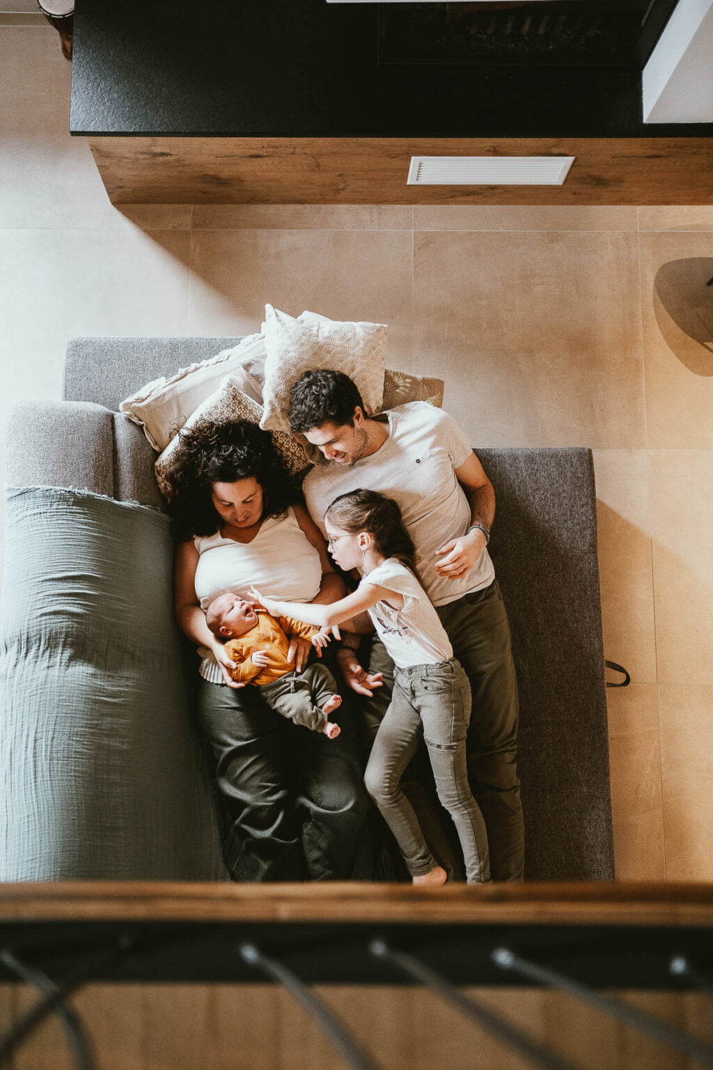Bébé allongé dans les bras de ses parents dans leur maison.