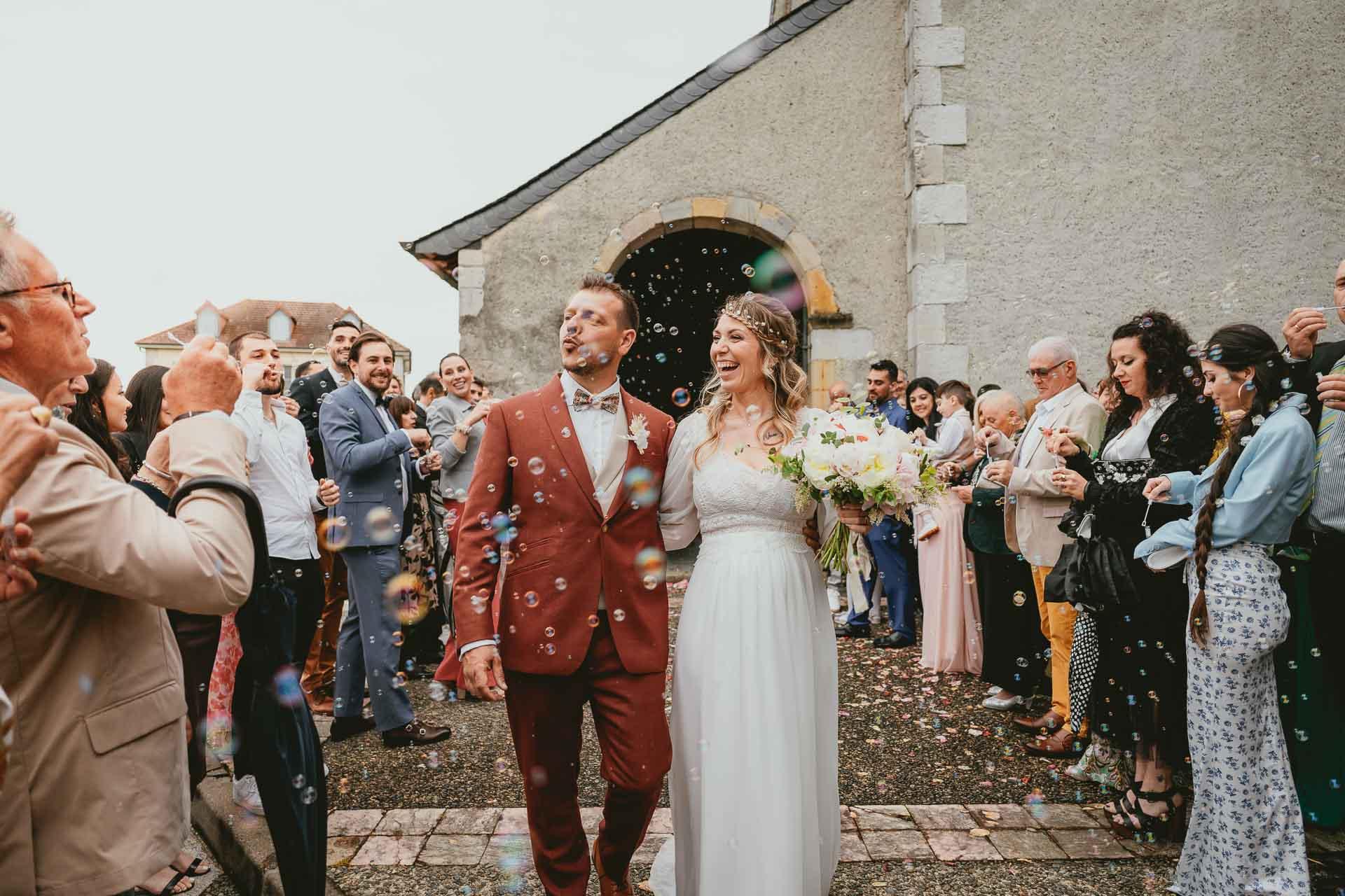 Des mariés sortent d'une église avec des confettis lancés sur eux après leur cérémonie de mariage hippie.