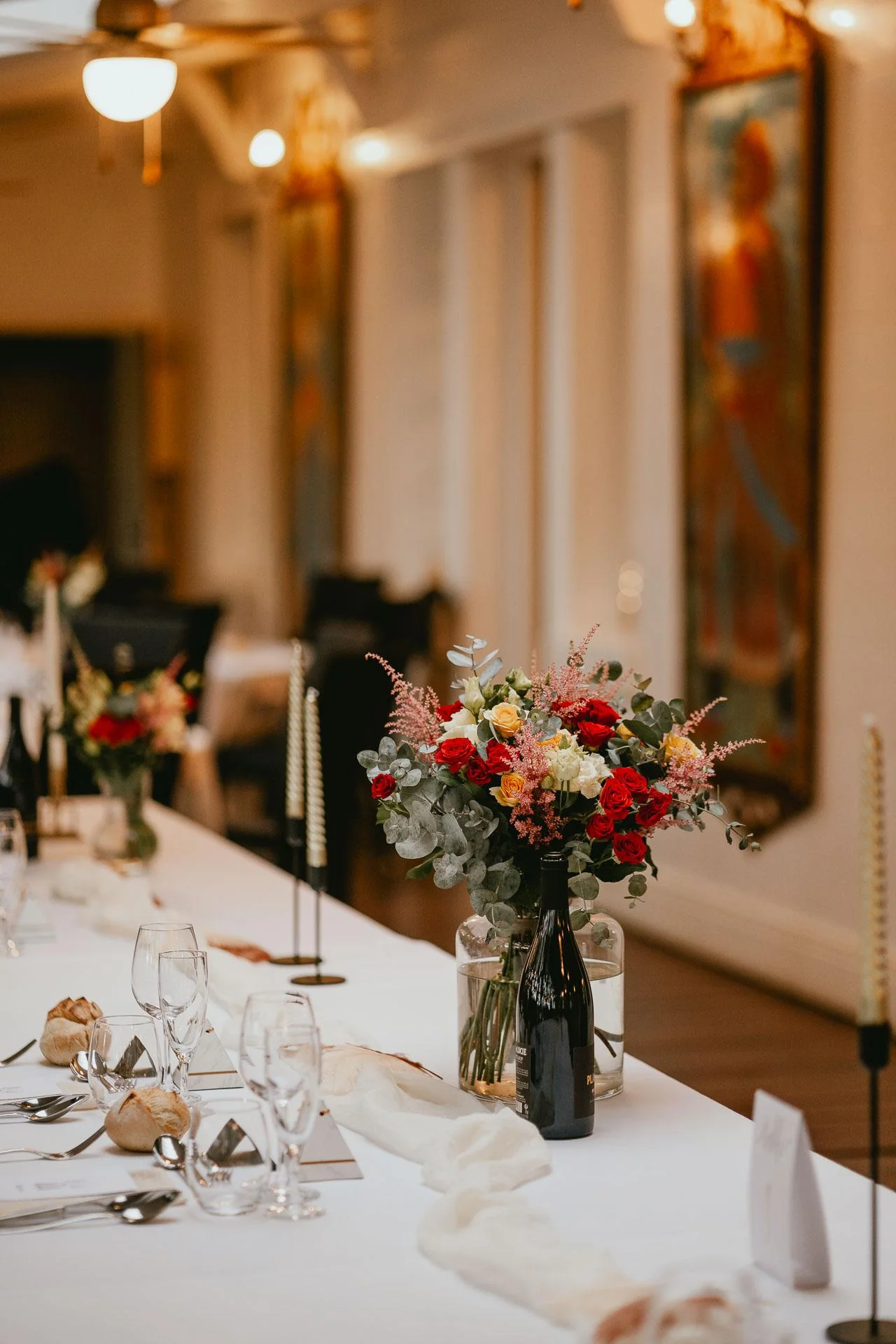 Une longue table dressée avec des fleurs, des verres à vin et des invitations "être témoin de mariage".
