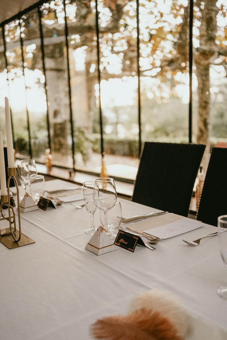Une table blanche avec des bougies et des plumes pour être temoin de mariage.