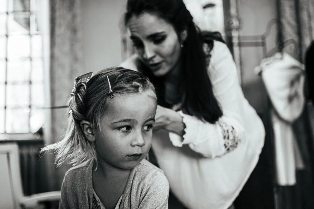 Une petite fille se fait coiffer par sa mère.