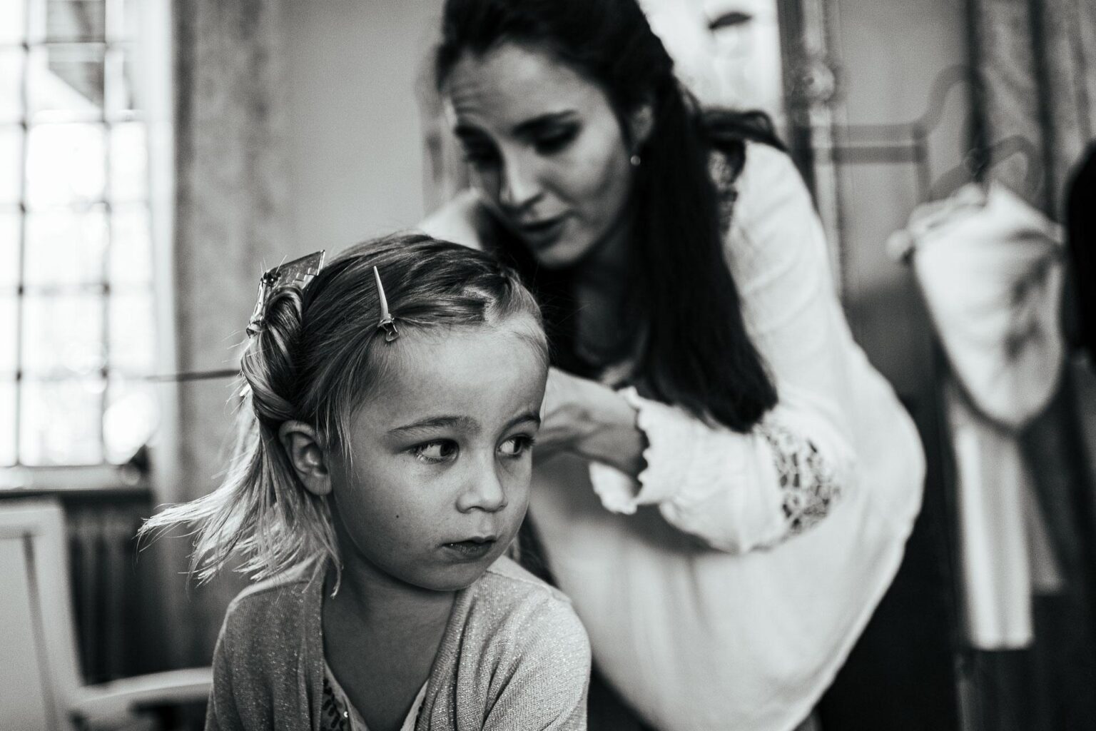 Une petite fille se fait coiffer par sa mère.
