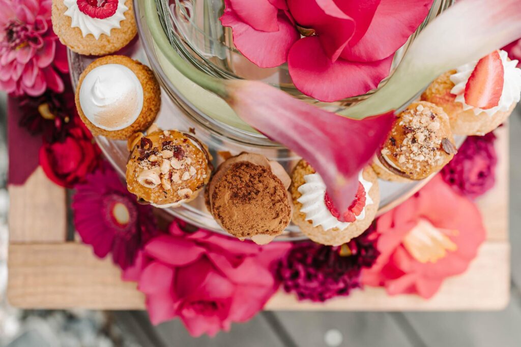 Un plateau de cupcakes et de fleurs de Jeanne et Lulu sur une table en bois.