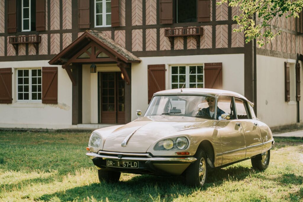 Une voiture ancienne, parfaite pour location voiture mariage landes, garée devant une maison.