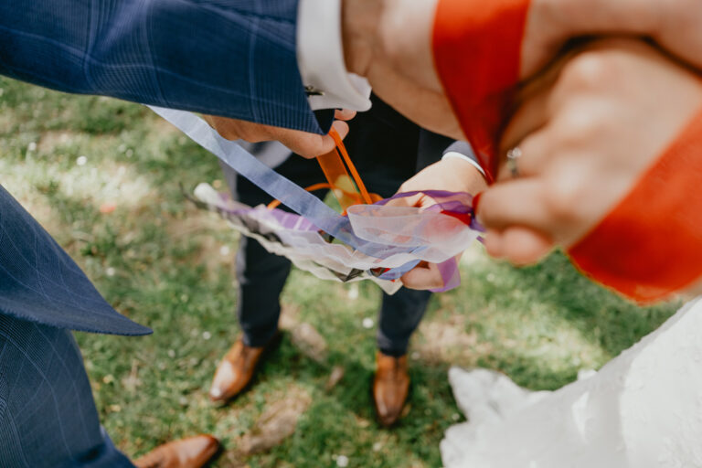 Un célébrant lors d'un mariage landais supervise les mariés attachant un ruban ensemble.