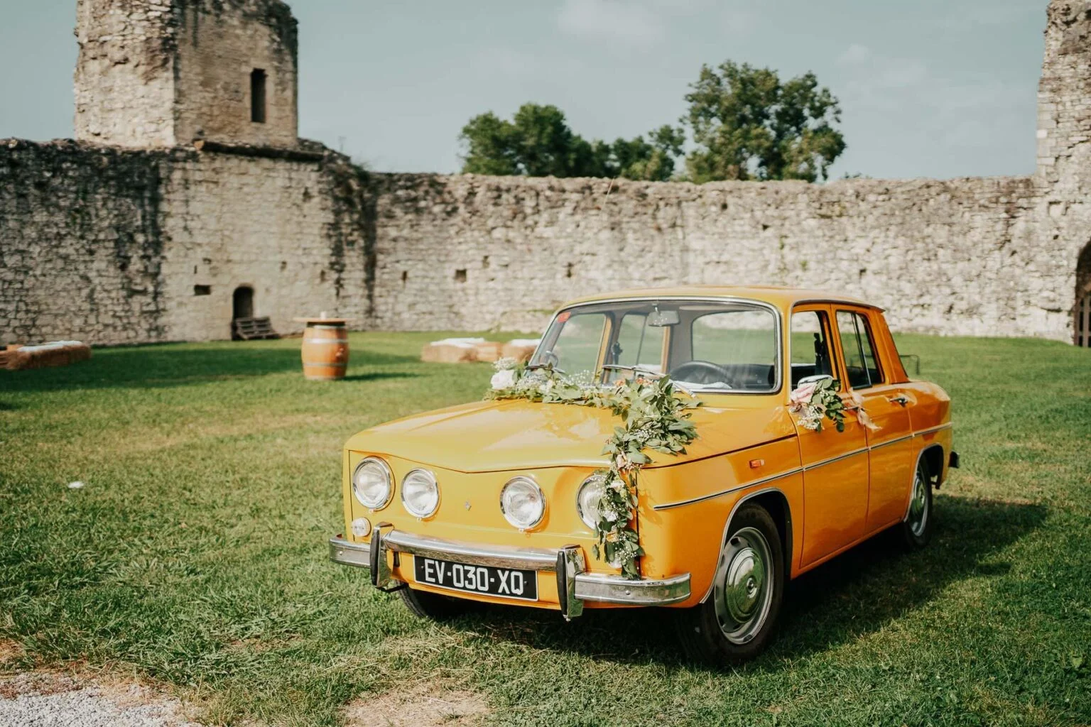 Une vieille voiture jaune garée devant un château.