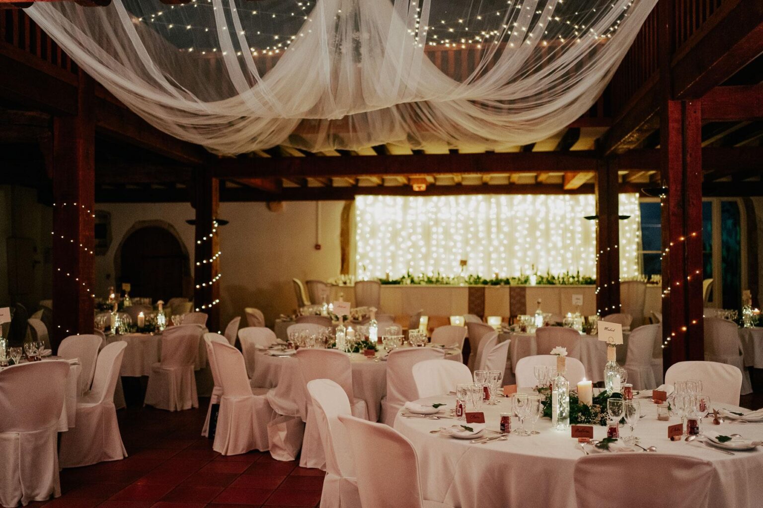 Une réception de mariage organisée avec des tables et des draps blancs.