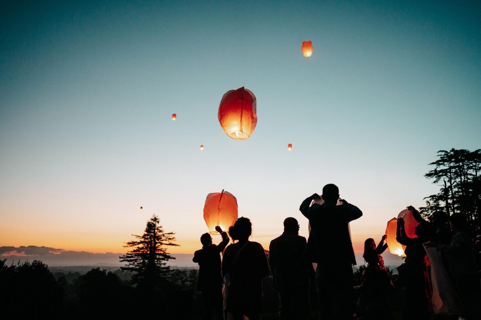 Un groupe de personnes regardant des lanternes voler dans le ciel.