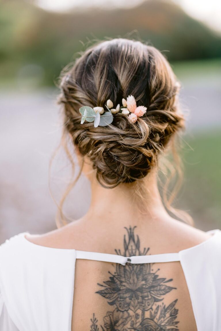 Une mariée avec un tatouage dans le dos et des fleurs des Landes dans les cheveux.