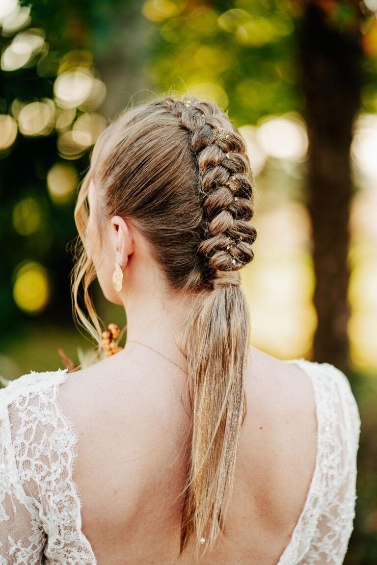 Une mariée coiffeuse dans une robe blanche avec une tresse en queue de cheval.
