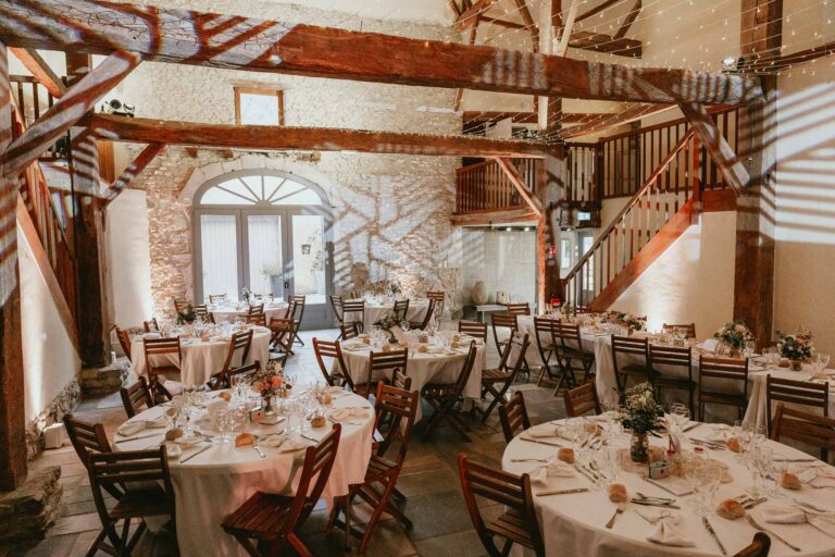 Une réception de mariage organisée dans une grange aux poutres en bois, avec un Dj mariage landais.