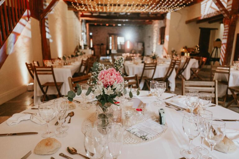 Une réception de mariage dans une grange avec des nappes blanches, des fleurs, et un DJ mariage landais.