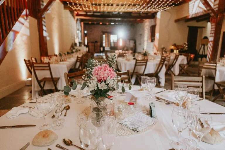 Une réception de mariage dans une grange avec des nappes blanches, des fleurs, et un DJ mariage landais.