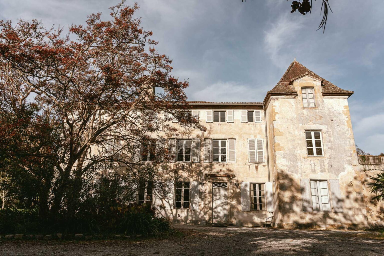Une vieille maison en pierre avec des arbres en arrière-plan.
