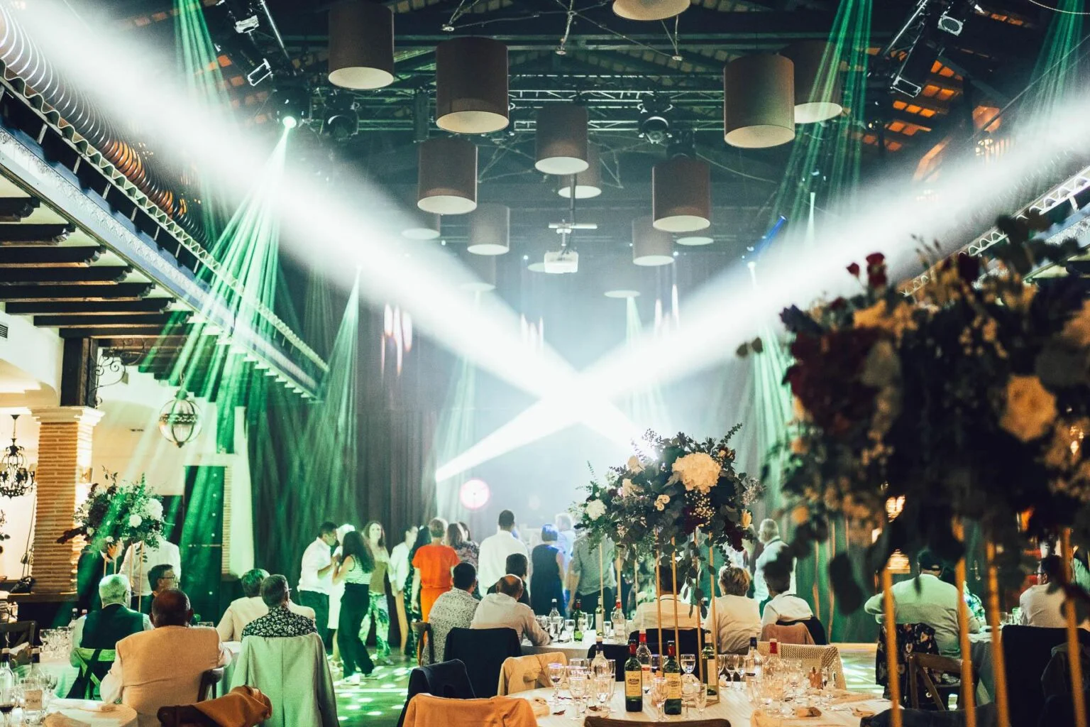 Une réception de mariage dans une grande salle avec un éclairage vert.