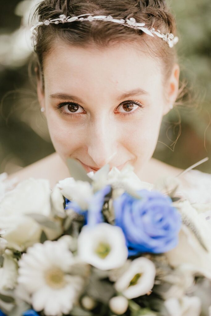 Une mariée tenant un bouquet de fleurs bleues et blanches provenant d'un mariage fleuriste landais.