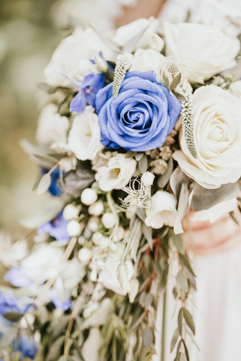 Une mariée tient un bouquet de mariée bleu et blanc conçu par un fleuriste mariage Landais.
