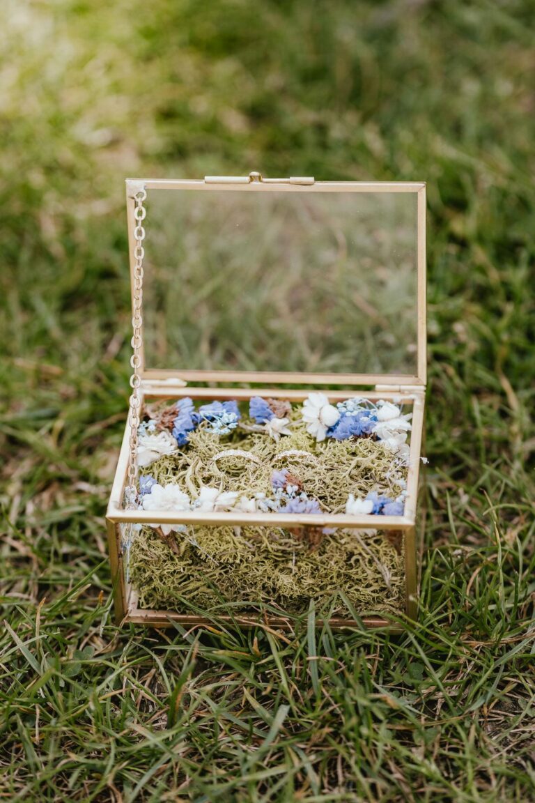 Une petite boîte en verre remplie de fleurs fleuristes sur l'herbe.