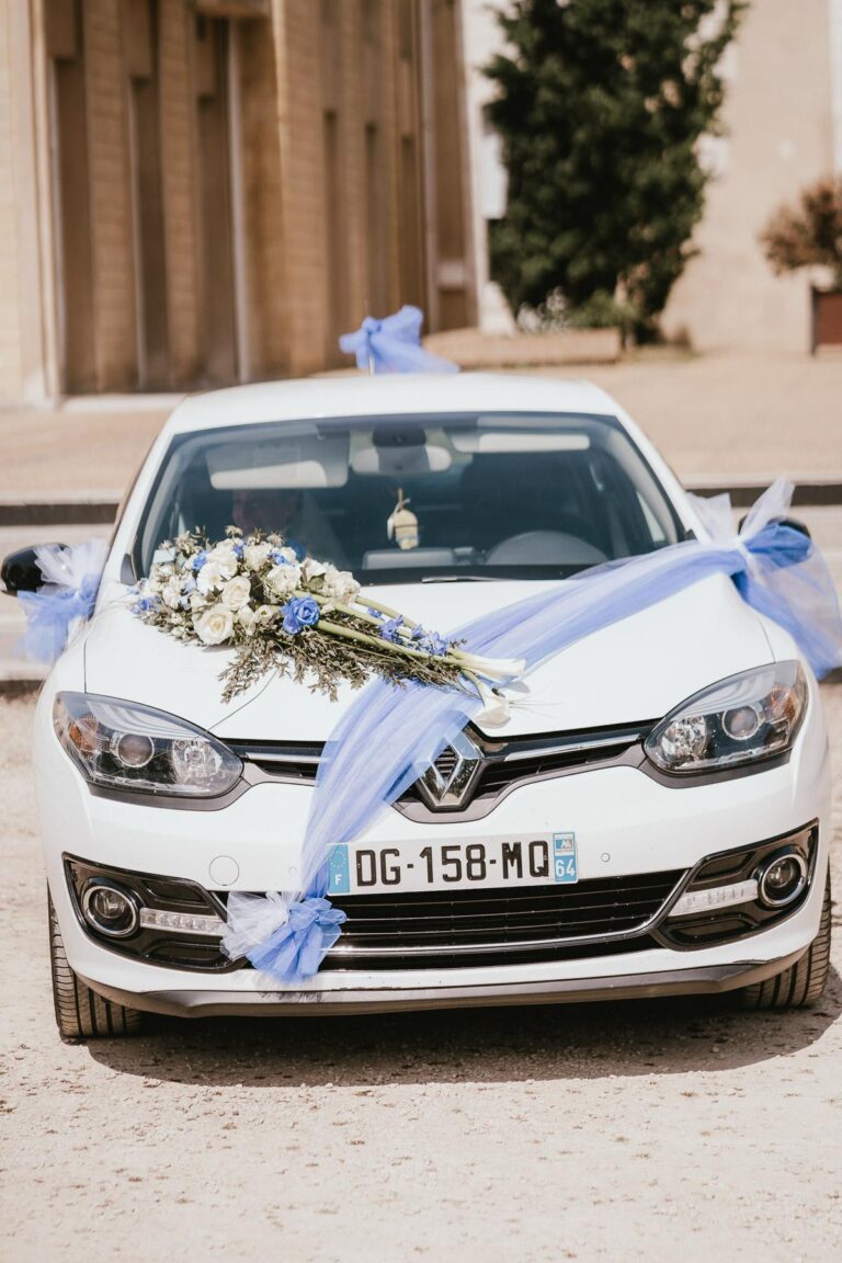 Une voiture de mariage blanche décorée de fleurs bleues et blanches par un fleuriste mariage landais.