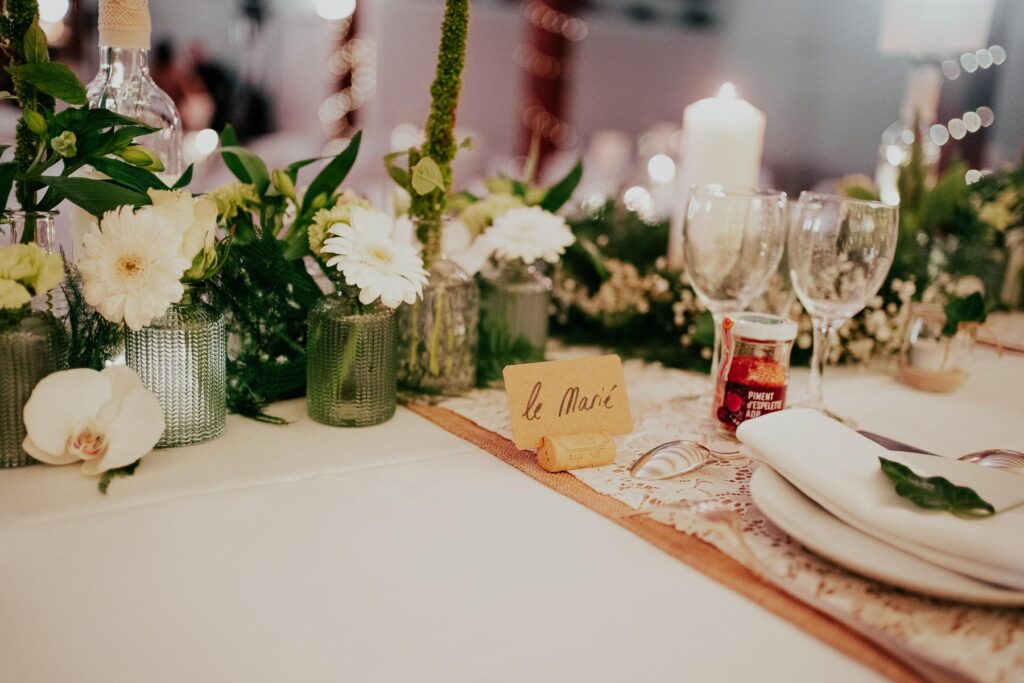 Une décoration de table avec des fleurs blanches d'un mariage fleuriste de Capbreton et un marque-place.