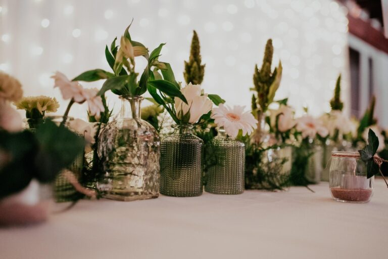Une table de fleurs vertes et blanches dans des bocaux en verre d'un fleuriste pour un mariage à Capbreton.