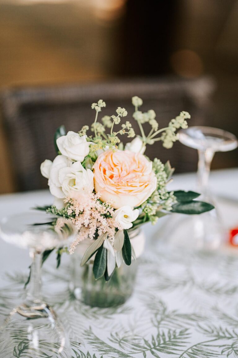 Un arrangement de roses blanches et de verdure sur une table par un fleuriste mariage landais.