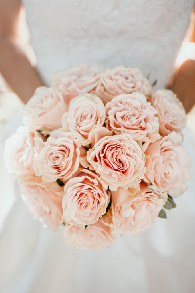 Une mariée tient un bouquet de roses roses confectionné par un fleuriste mariage landais.