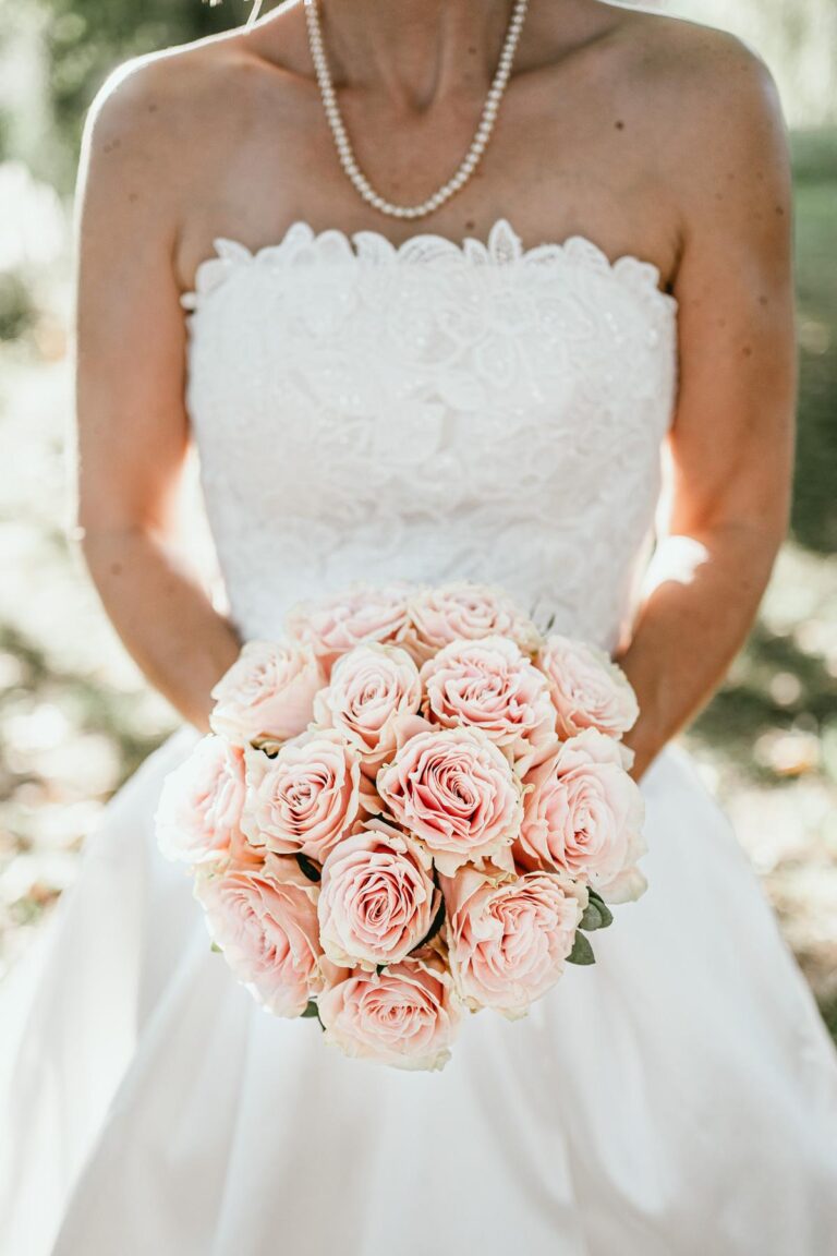 Une mariée tenant un bouquet de roses roses conçu par un fleuriste spécialisé dans les mariages landais.