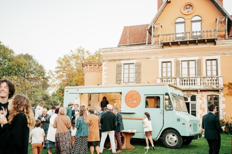 Un groupe de personnes debout autour d’un food truck landais devant une maison.