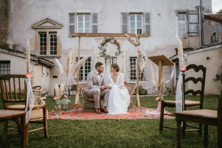 Une mariée et un marié assis sur des chaises devant une maison.