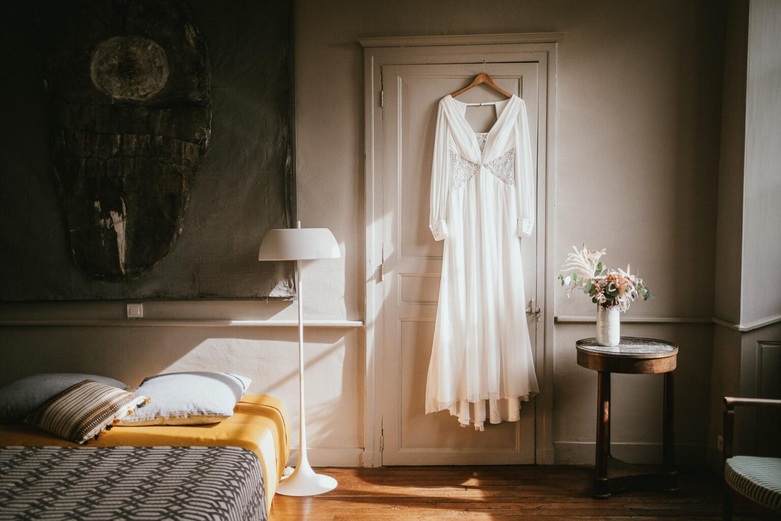 Une robe de mariée est accrochée à un cintre dans une chambre.