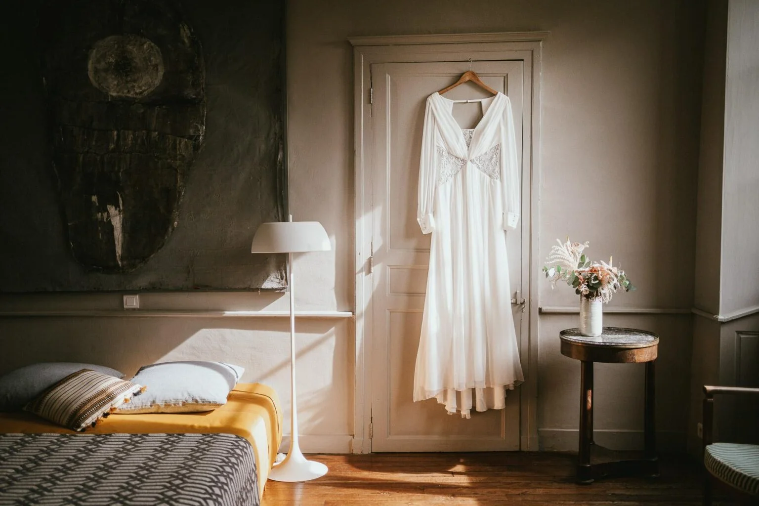 Une robe de mariée est accrochée à un cintre dans une chambre.