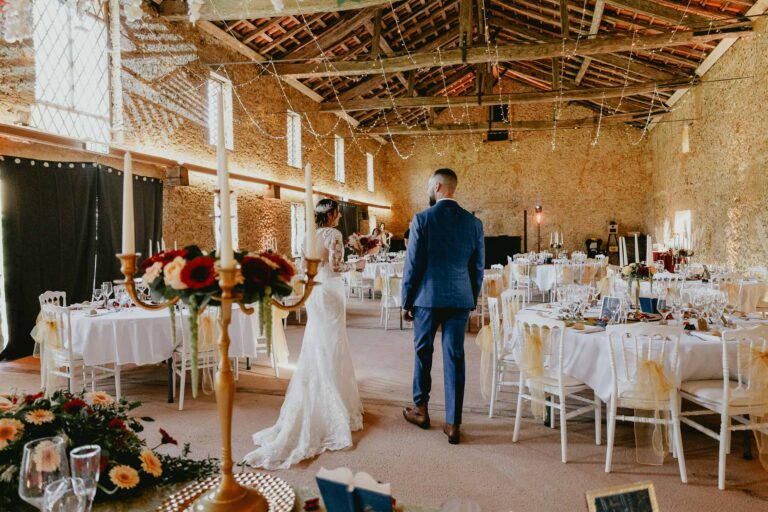 Des mariés marchant dans l'allée lors d'une réception de mariage dans une grange, avec location matériel mariage Landes.