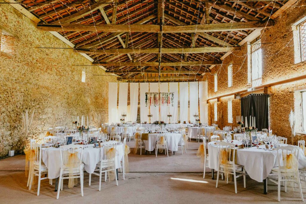 Une réception de mariage dans une grange avec tables et chaises, mettant en vedette location matériel mariage Landes.