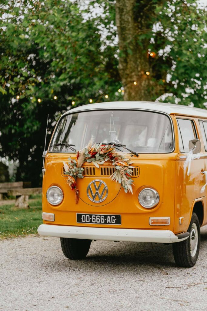 Le bus VW orange d'un fleuriste est garé devant un arbre.