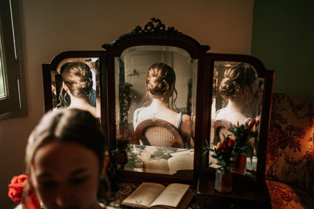 Une femme se regarde dans le miroir en pensant à sa coiffeuse pour son prochain mariage dans les Landes.