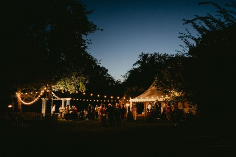 Une réception de mariage en plein air le soir avec des guirlandes lumineuses.
