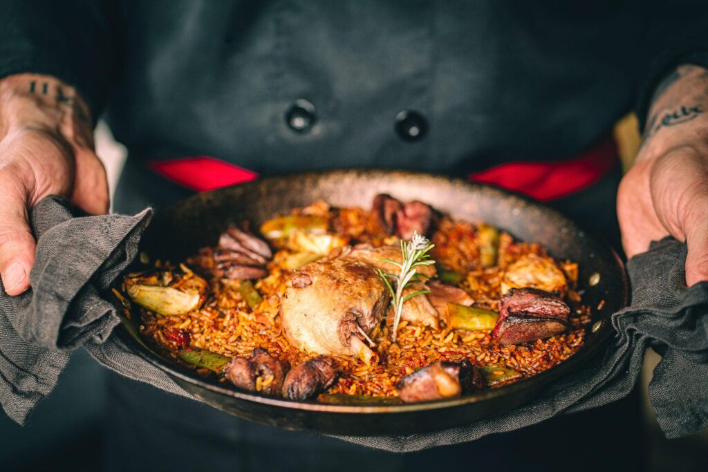 Un chef tient une poêle pleine d'Arroz Y Tapas.