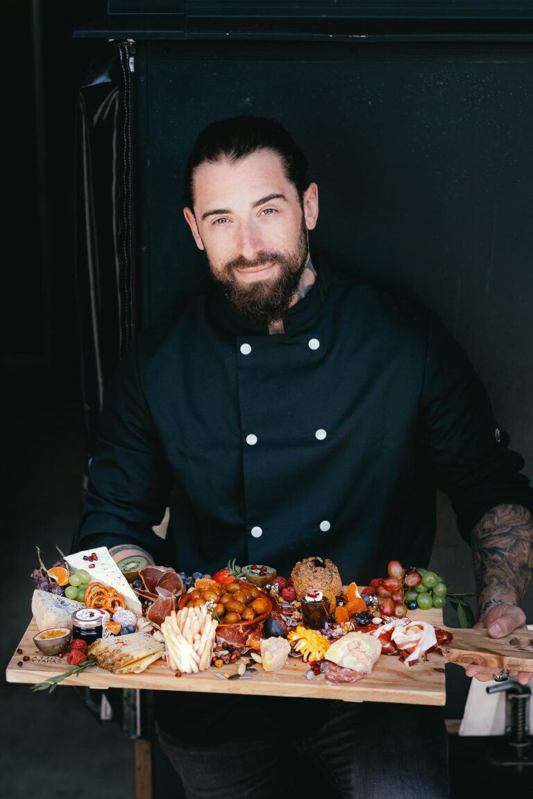 Un homme barbu tenant un plateau d'Arroz Y Tapas.