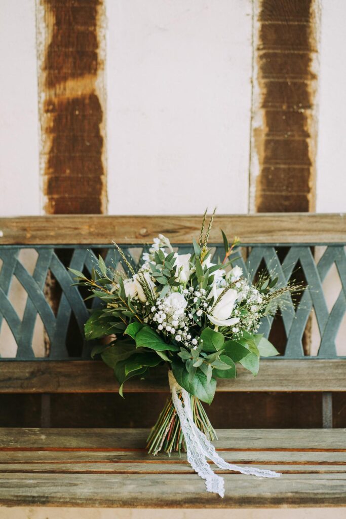 Un bouquet de mariage fleuriste landais est posé sur un banc en bois.