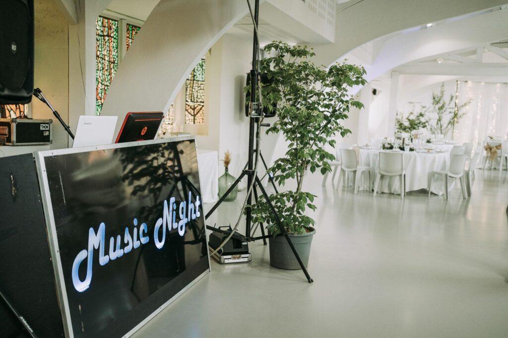 Une salle avec une table et des chaises blanches et une enseigne Djmariage Landes.