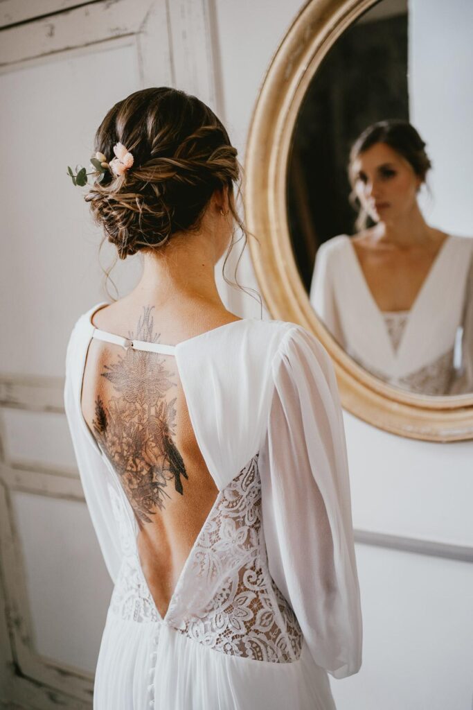 Une mariée vêtue d’une robe de mariée blanche avec un tatouage sur le dos.