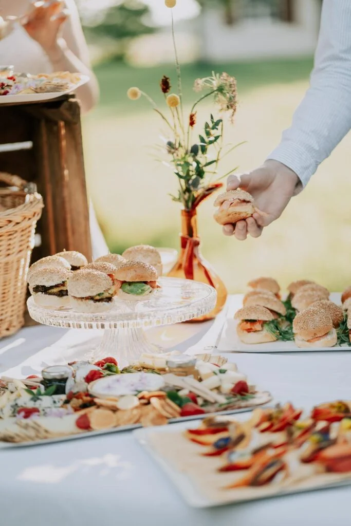 Une table remplie de nourriture et de boissons lors d'un mariage en plein air sur le thème de la Biarritz Brunch Box.