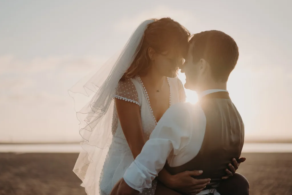 Des mariés s'enlacent sur la plage au coucher du soleil dans les Landes.