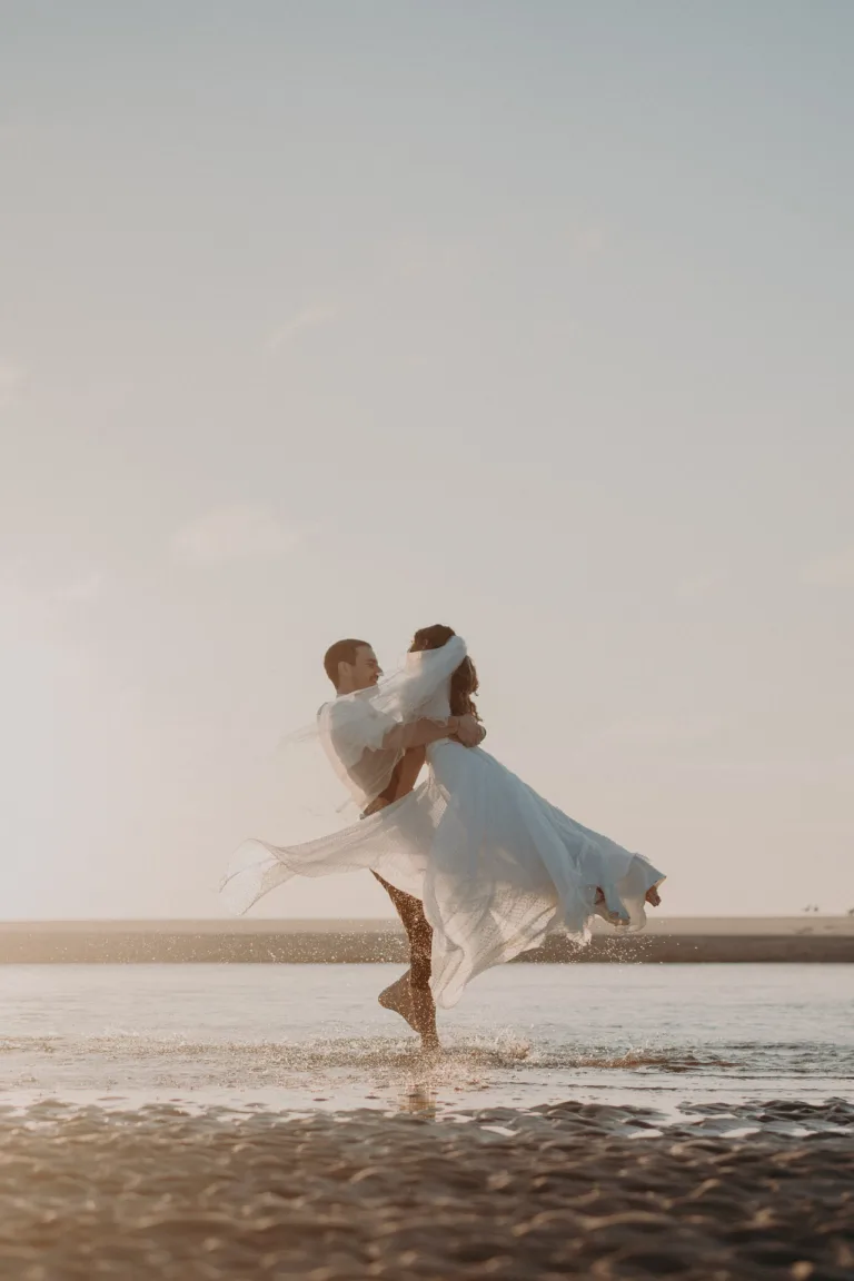 Une mariée et un marié dansant sur la plage au coucher du soleil dans l'après.