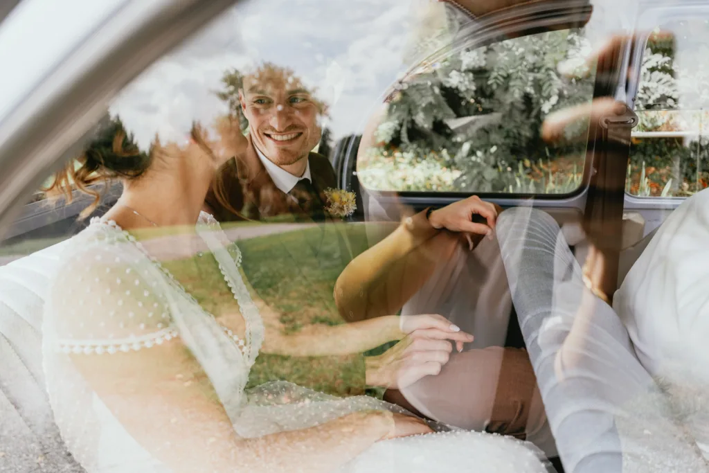 Des mariés assis sur la banquette arrière d'une voiture après leur mariage à la grange de Meysonnave.